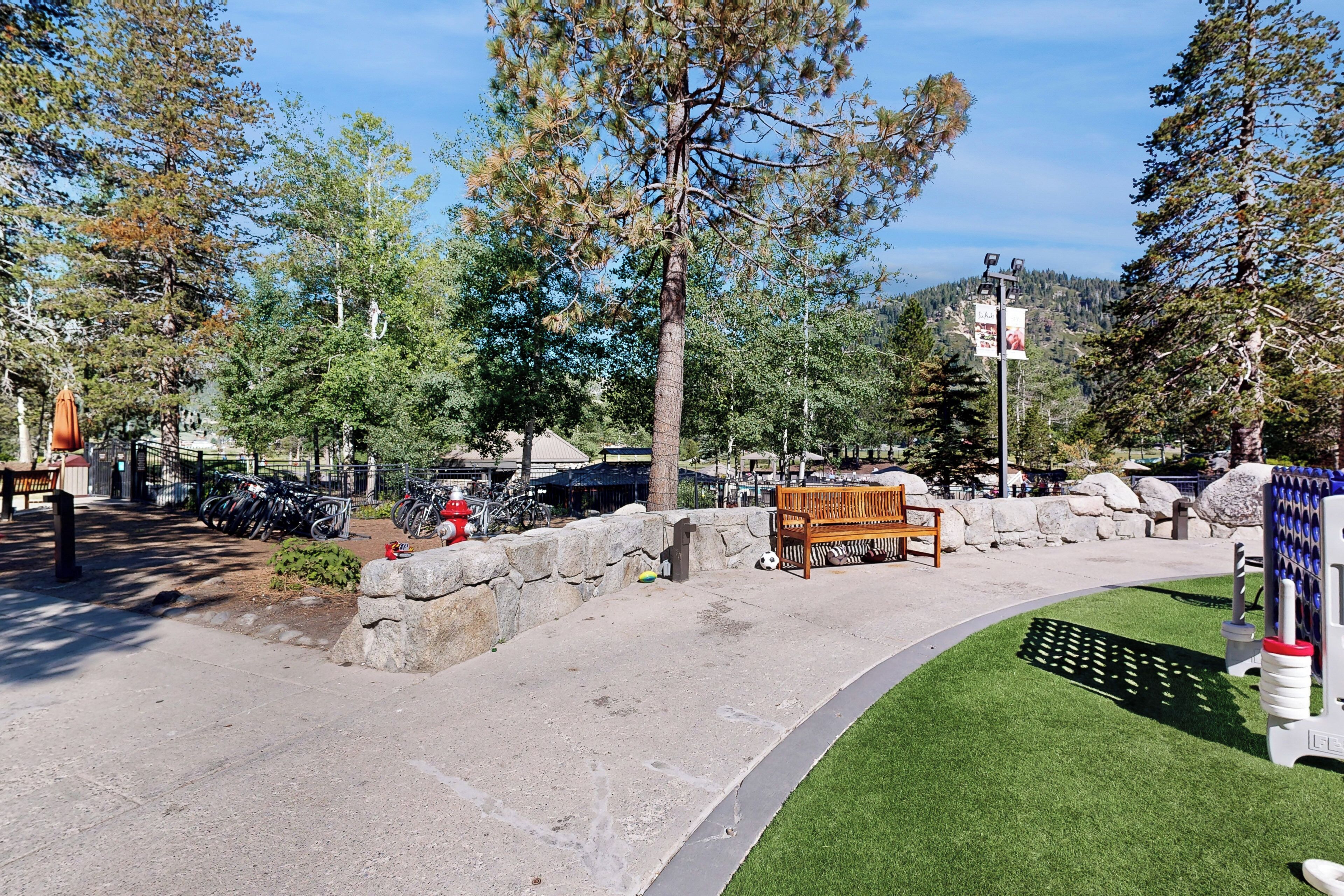 A park with a paved walkway, benches, a soccer goal, and a playground area.