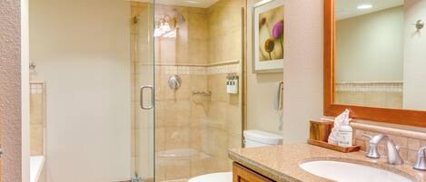 A modern bathroom with a glass-enclosed shower, a white toilet, and a granite countertop sink.