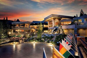 A modern hotel with a spacious outdoor area, multiple dining options, and a prominent statue. - 2BR Condo w/ Pool Access, Hot Tub, & ski In/out (Olympic Valley)