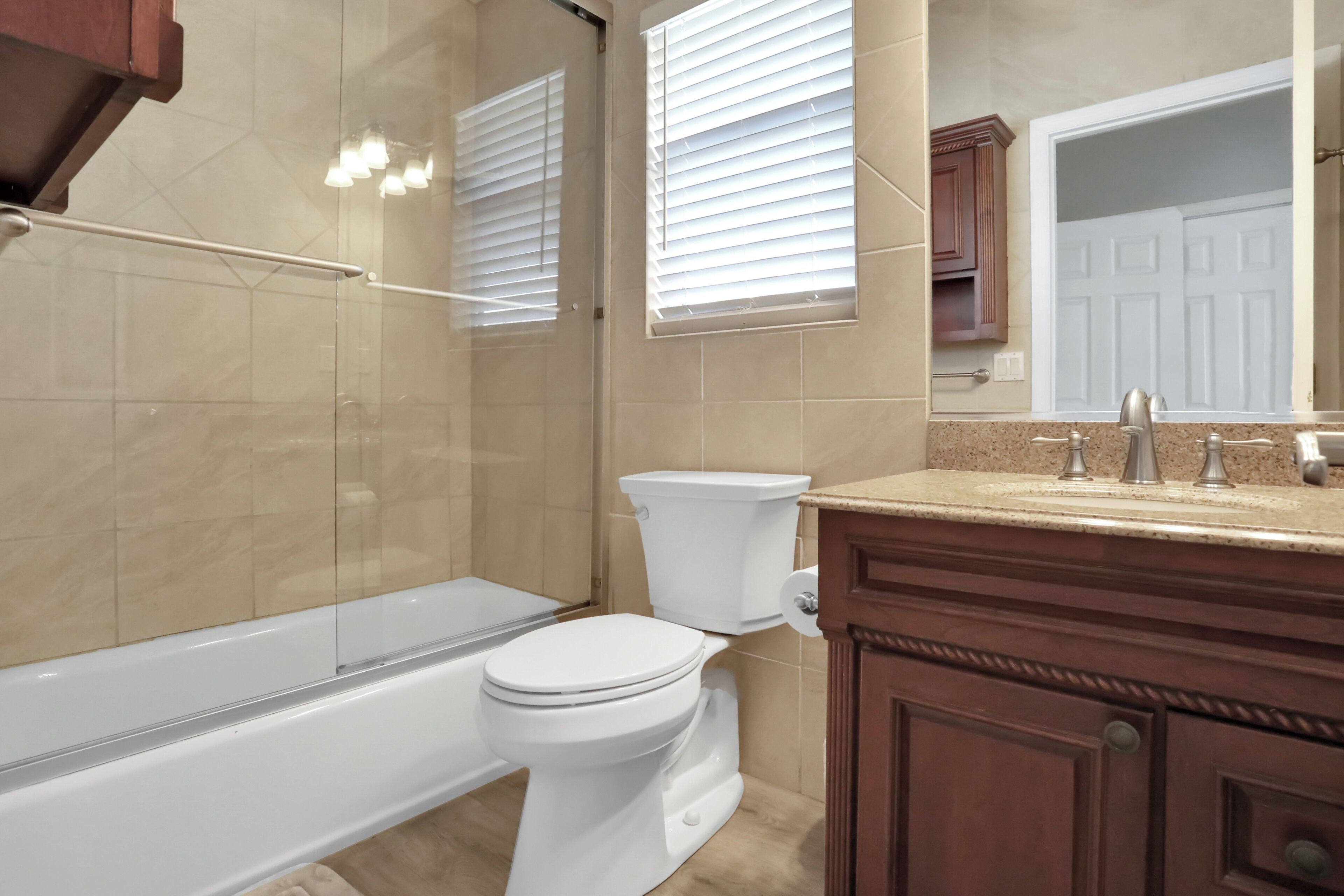 A bathroom with a bathtub, toilet, and vanity with a mirror.