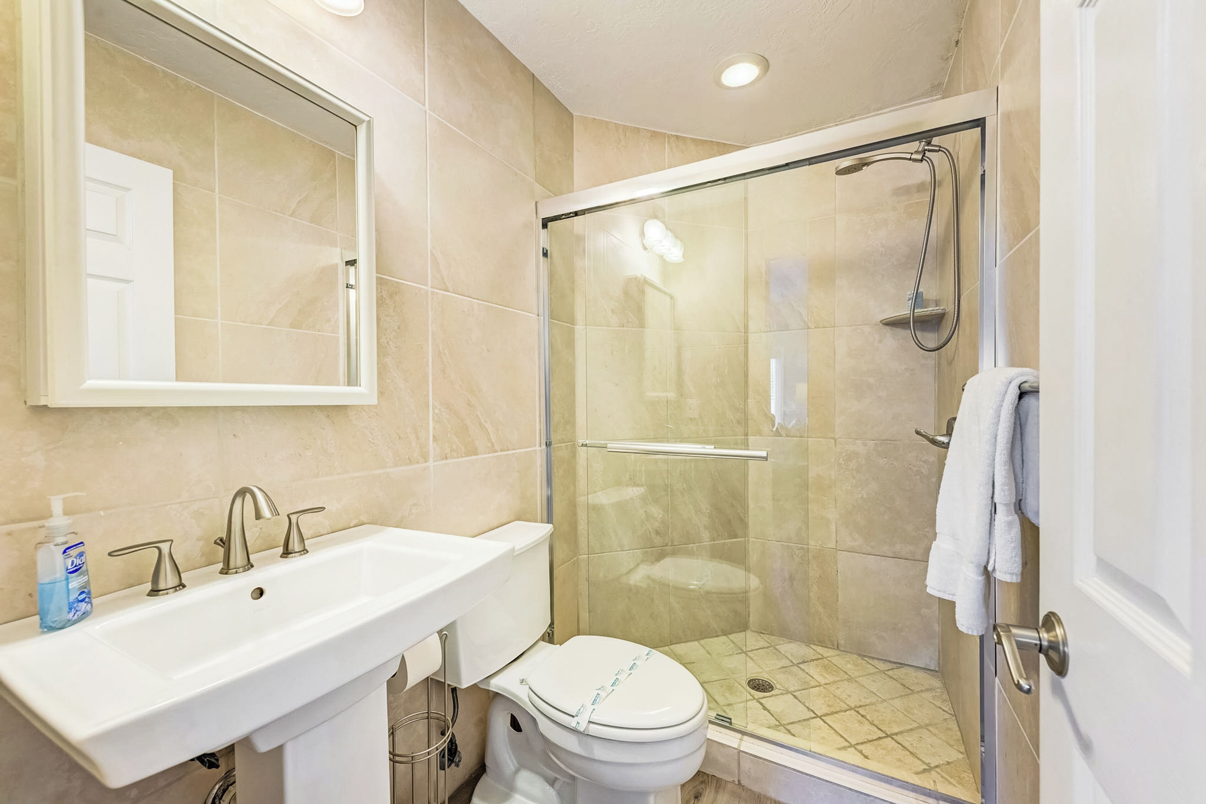 Une salle de bain avec un lavabo blanc, un miroir et des toilettes.