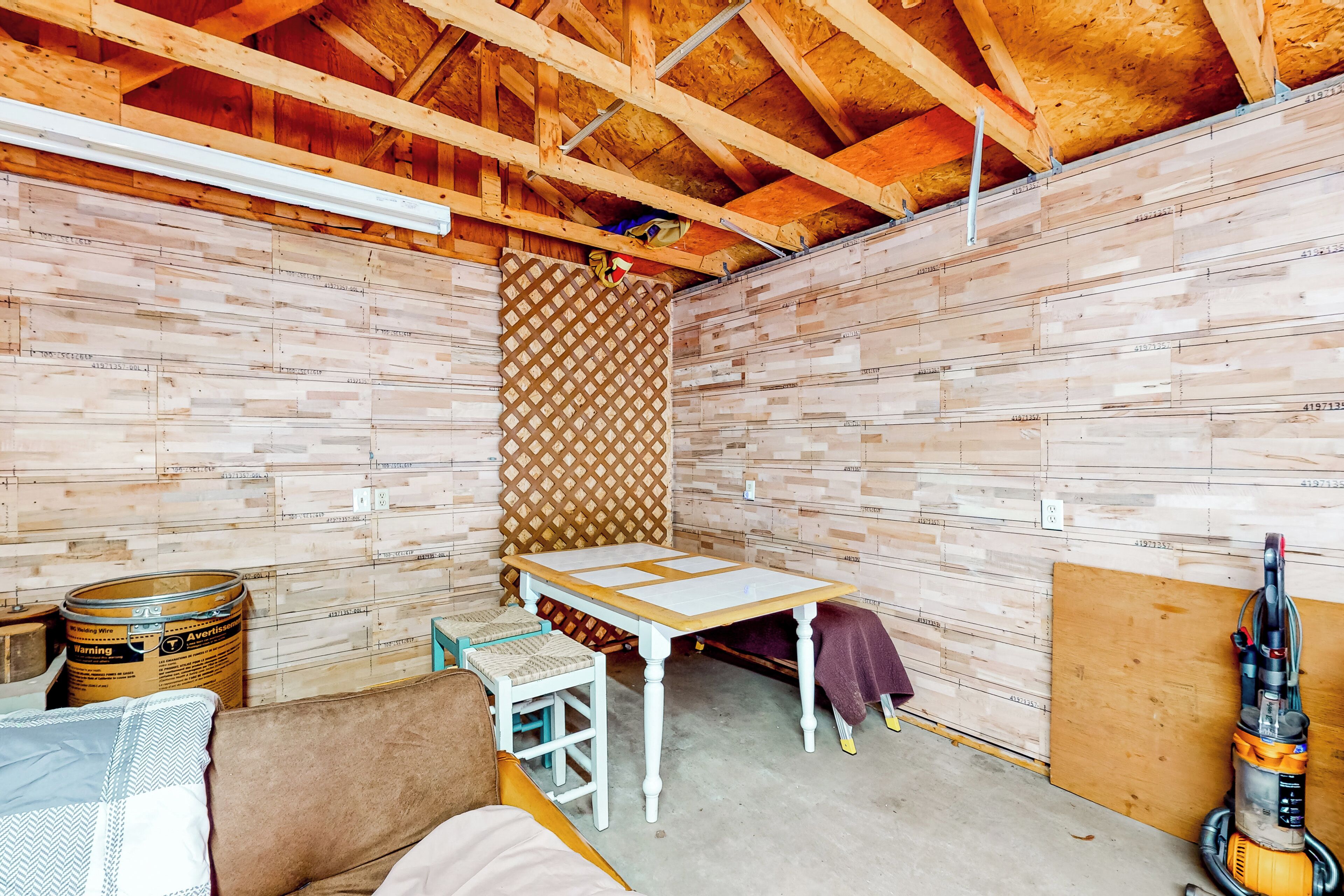 A room with exposed wooden beams, a table, a chair, and a vacuum cleaner.