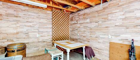 A room with exposed wooden beams, a table, a chair, and a vacuum cleaner.