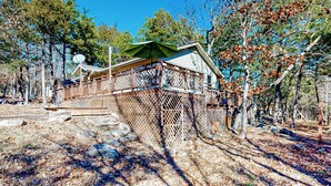 Une cabane dotée d’une terrasse, entourée d’arbres et offrant une vue sur un ciel dégagé.