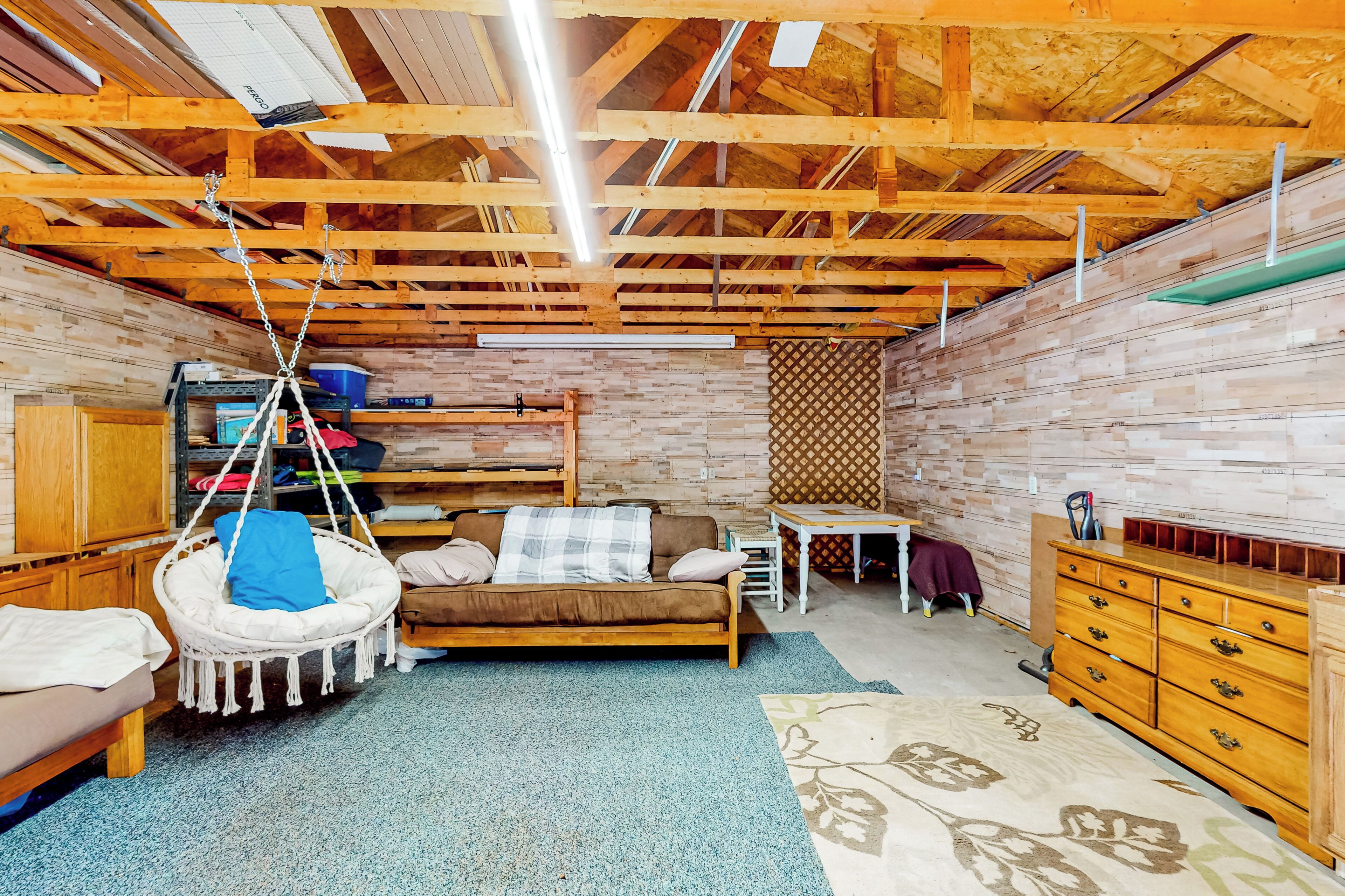 Una habitación acogedora con techo de madera, una silla colgante, un sofá, una mesita y un aparador.