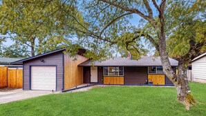 Une maison moderne de plain-pied, dotée d’un garage, d’un porche abrité et d’une pelouse bien entretenue.