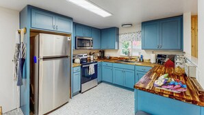 Une cuisine avec des meubles bleus, des appareils en acier inoxydable et un plan de travail en bois.