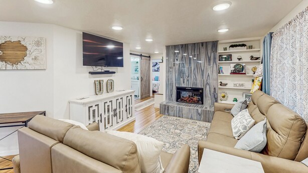 Un salon moderne avec un canapé, un téléviseur, une cheminée et des étagères décoratives.