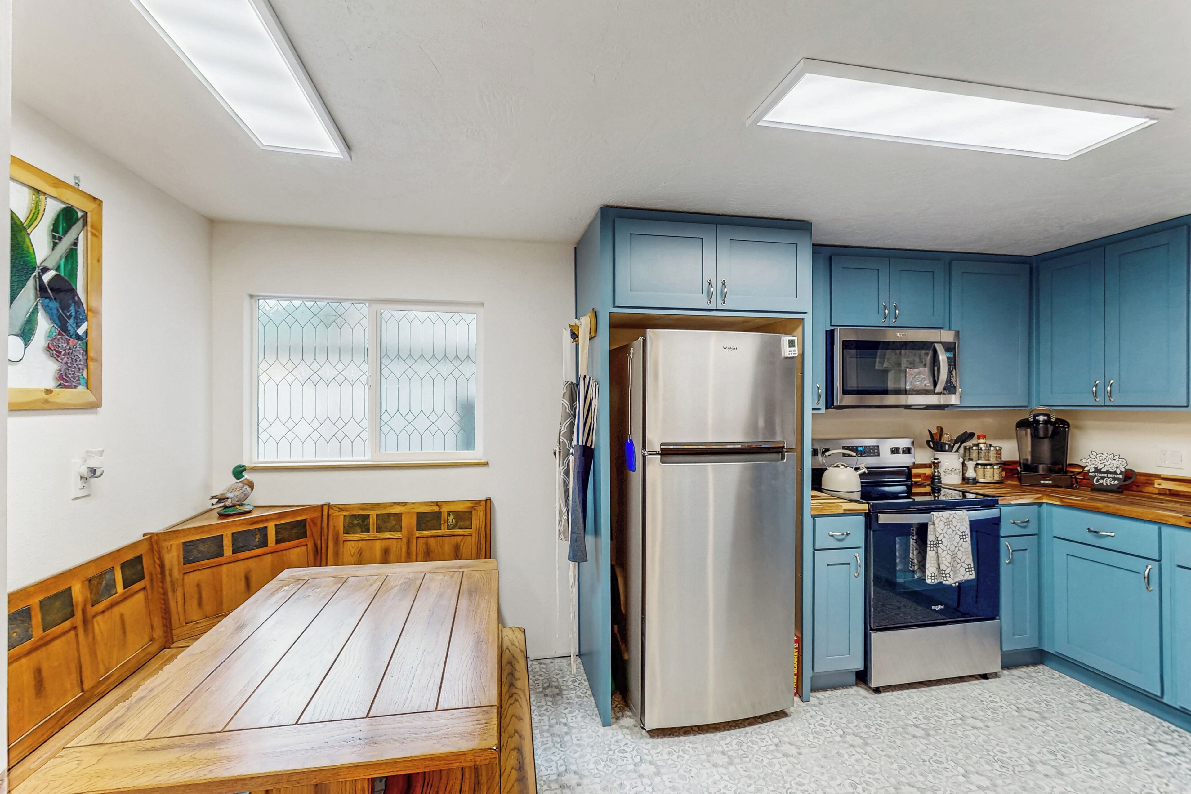 A kitchen with blue cabinets, a stainless steel refrigerator, a microwave, and an oven.