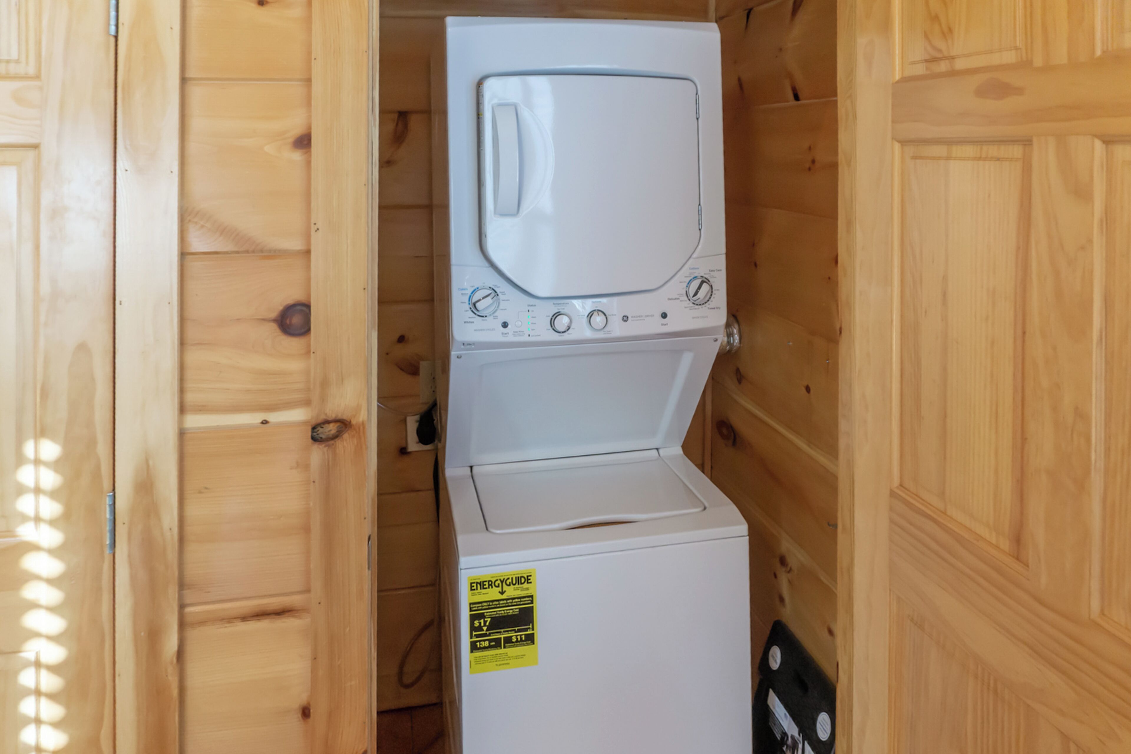 Un lave-linge et un sèche-linge blancs, dotés d’une étiquette ENERGYGUIDE, placés dans un meuble en bois.