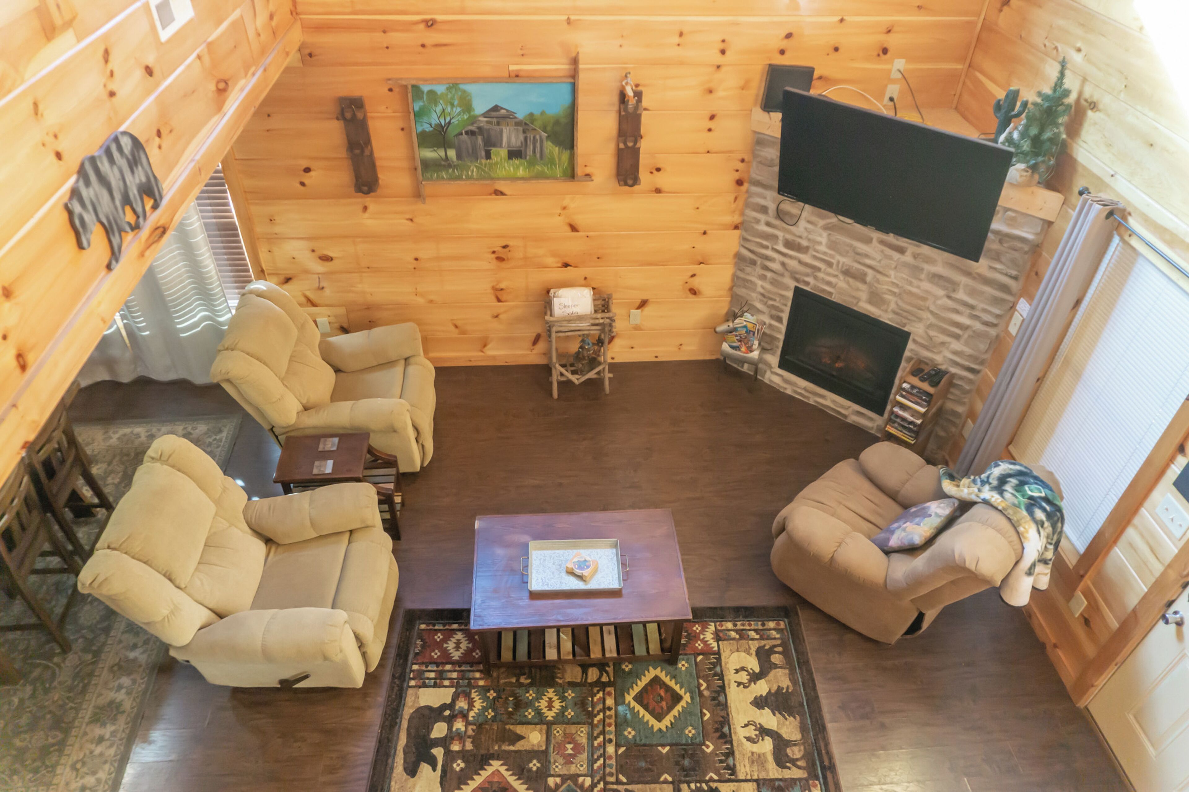 Interior acogedor de una cabaña de madera con chimenea, dos sofás, una mesa de centro y una alfombra.
