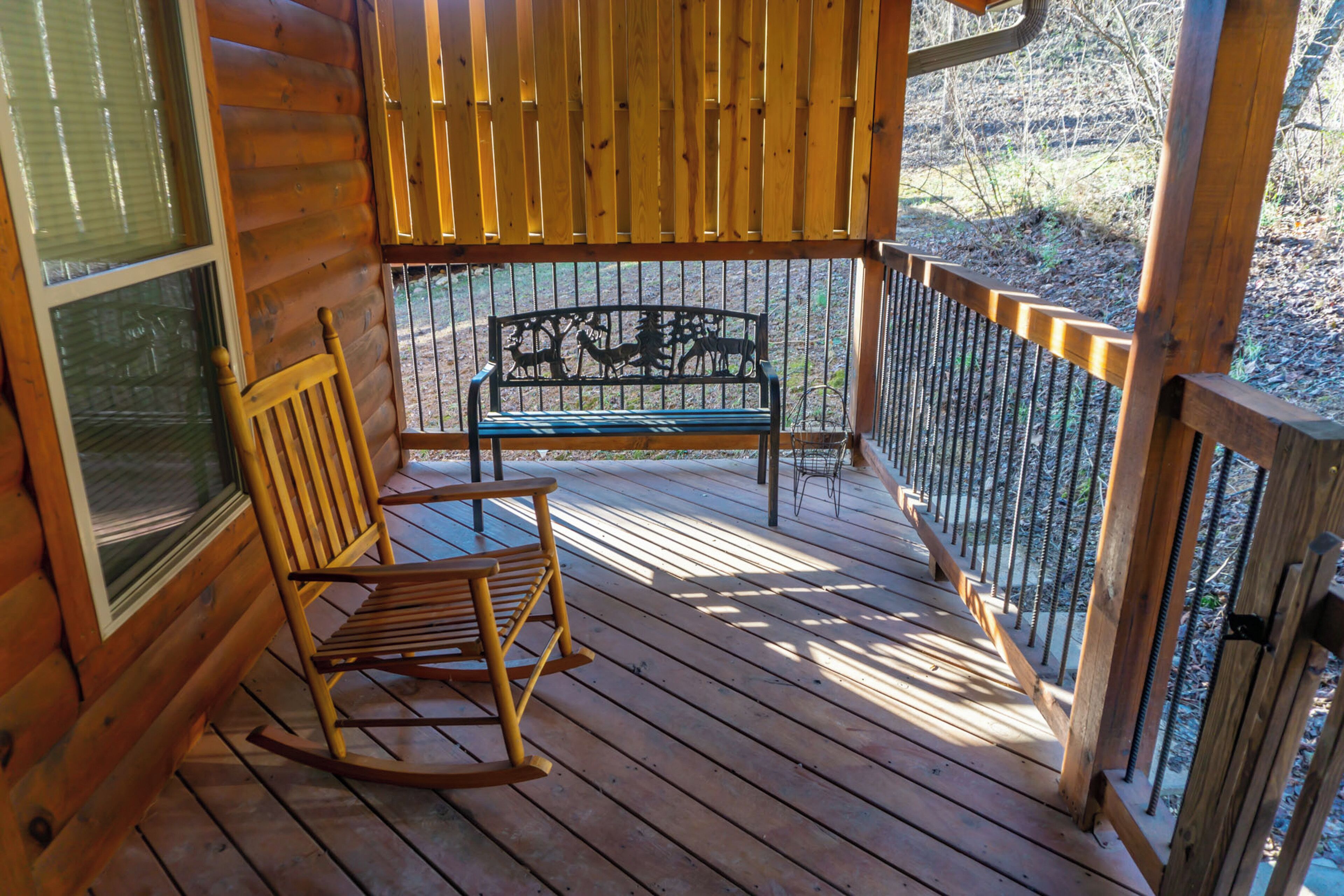 A wooden deck with a rocking chair and a metal bench.