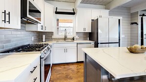 Una cocina moderna con armarios blancos, electrodomésticos de acero inoxidable y encimera de mármol.