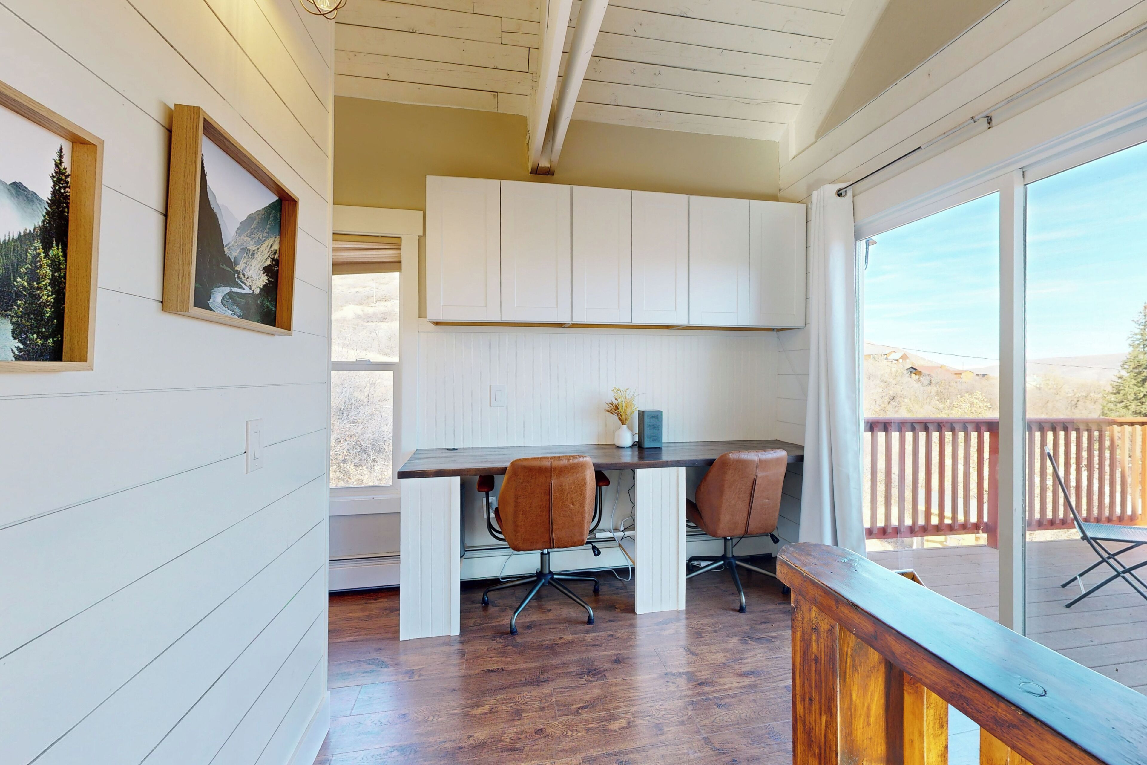 A modern kitchen with white cabinets, a wooden countertop, and two brown chairs.