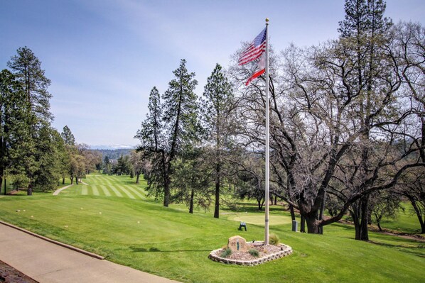 Un parcours de golf avec un mât de drapeau, des arbres et un ciel dégagé.