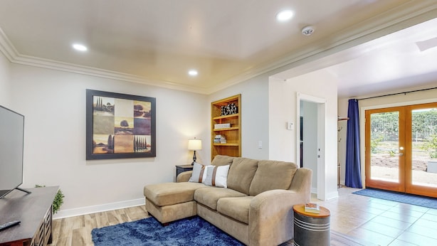 A living room with a sectional sofa, a coffee table, a TV, and a bookshelf. - Two Dog-friendly Home, Close to Wine Country (Fallbrook)