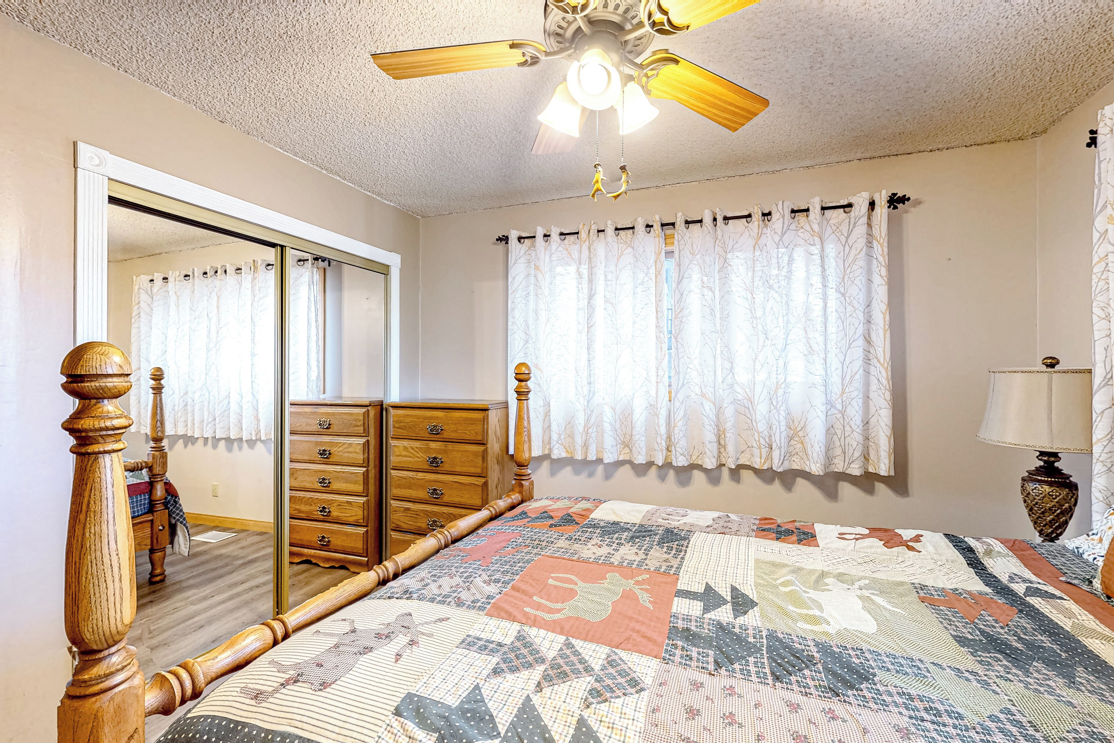 Ein Schlafzimmer mit einem hölzernen Bett, einem Schminktisch, einem Spiegel und einem Deckenventilator.