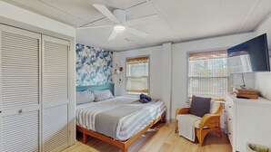 A bedroom with a bed, a ceiling fan, a window with blinds, a TV, and a wardrobe. - Entire House - Serenity in Surf City (Holly Ridge)