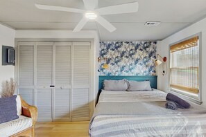 Quarto com cama, ventoinha no teto, janela com persianas e guarda-roupa.