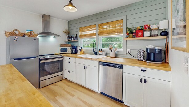 A modern kitchen with stainless steel appliances, wooden countertops, and a window with blinds. - Entire House - Serenity in Surf City (Holly Ridge)