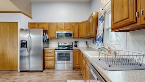 A modern kitchen with wooden cabinets, stainless steel appliances, and a dish rack.