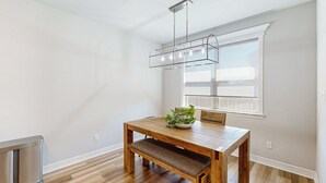 Un espace repas comprenant une table en bois, un banc et un luminaire suspendu.