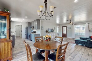 A spacious kitchen with a central island, wooden dining table with chairs, and a chandelier. - 3BR Family-friendly Home w/ Patio & BBQ (Fredericksburg)