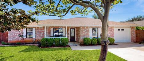 A residential house with a brick facade, a front porch, and a well-maintained lawn.