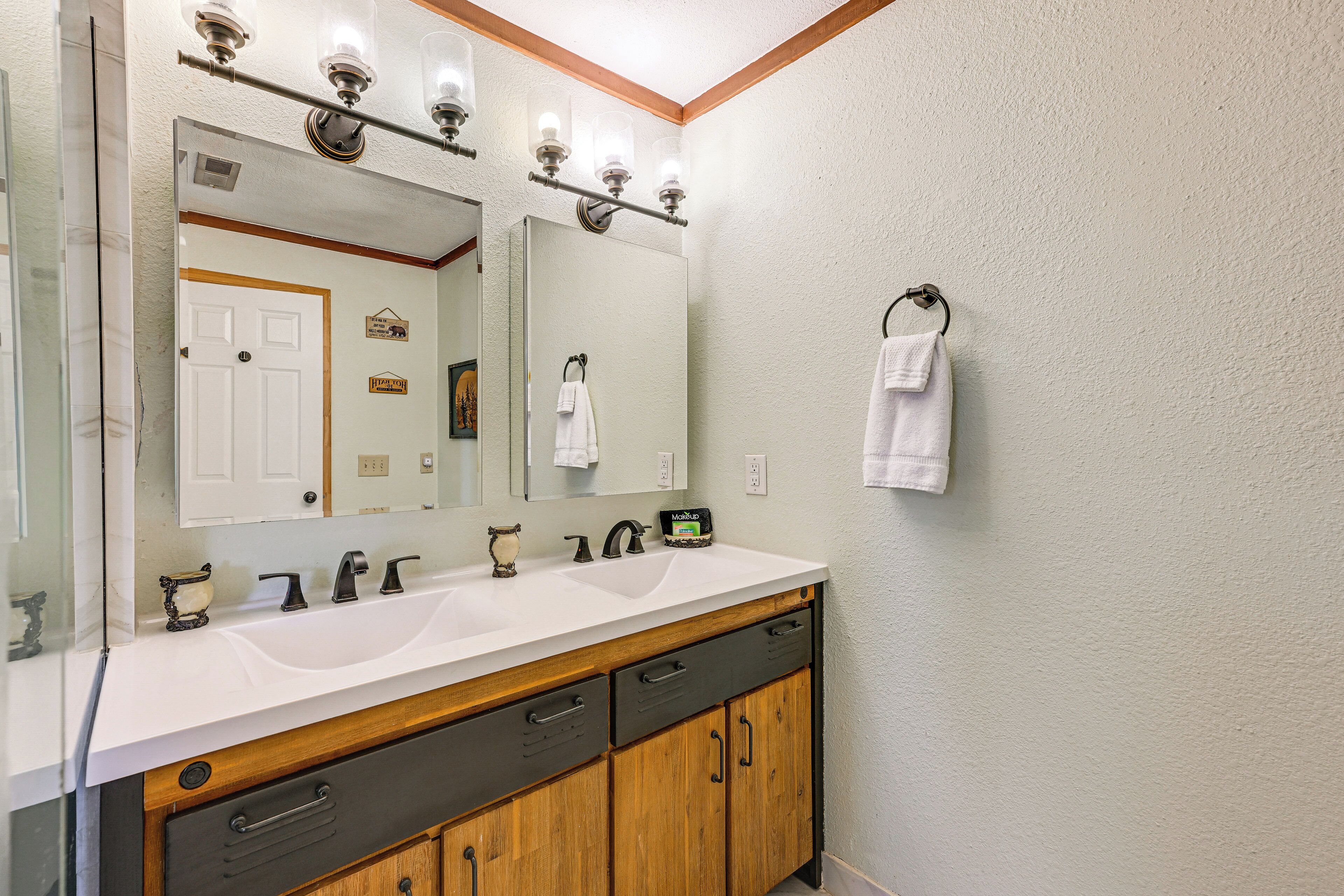 A bathroom with a white sink, a large mirror, wooden cabinets, and a towel rack.