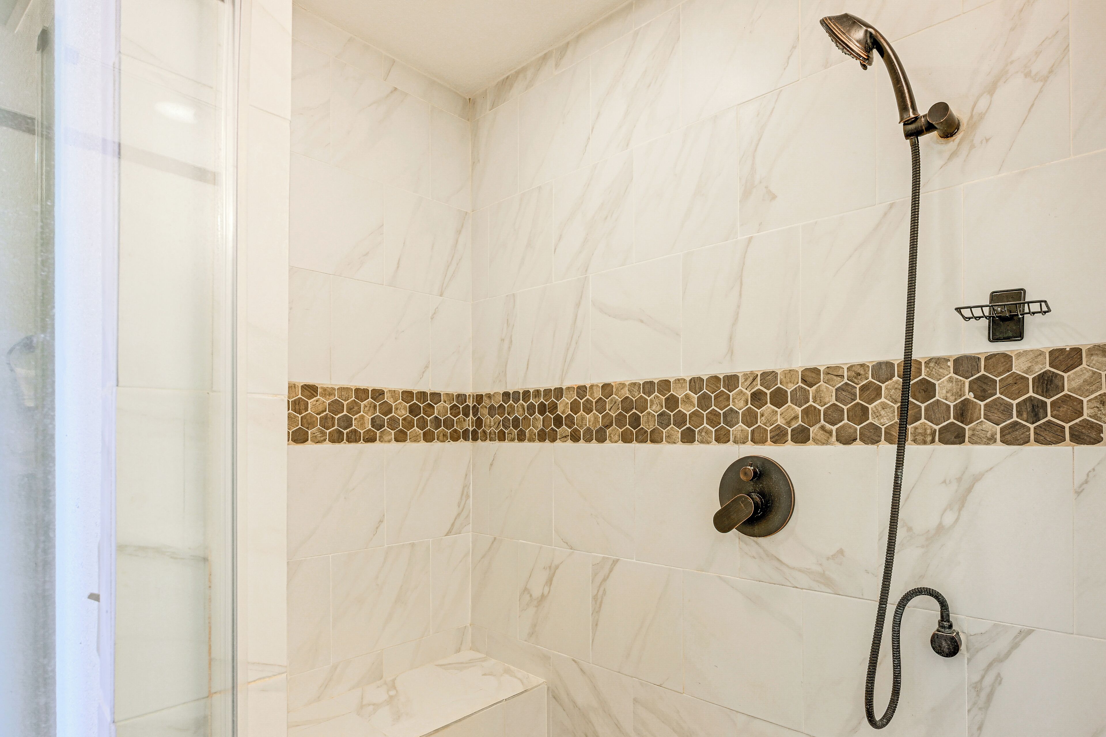 A shower area with a glass door, a showerhead, and a control knob.