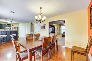 A dining area with a wooden table and chairs, a chandelier, and a kitchen in the background. - Wooded Trail On-site, Spacious Simpsonville Home (Simpsonville)