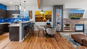 A modern kitchen with a central island, bar stools, and a dining table. - New Listing! Walk to City Park & Restaurants |  Extended Stays | Central AC (Denver)