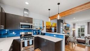 A modern kitchen with a central island, dark cabinetry, and blue backsplash. - New Listing! Walk to City Park & Restaurants |  Extended Stays | Central AC (Denver)