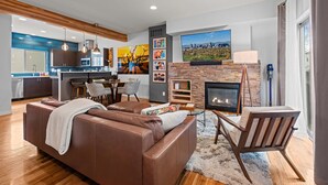 A modern living room with a brown leather sofa, a fireplace, and a dining area with a table and chairs. - New Listing! Walk to City Park & Restaurants |  Extended Stays | Central AC (Denver)