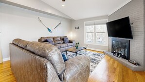 Una sala de estar con un sofá de cuero, una mesa de centro, una chimenea y un televisor montado en la pared.