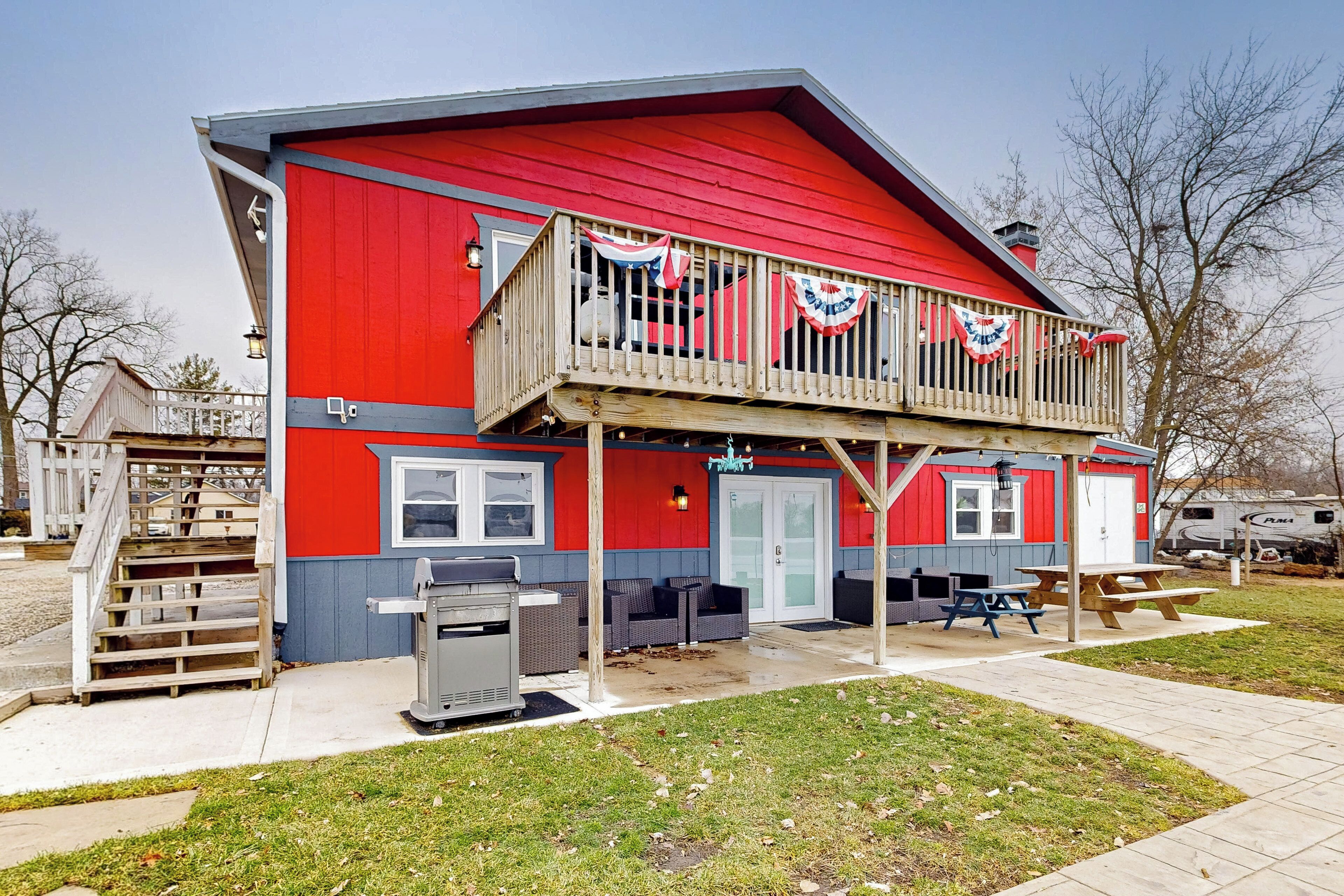 A red building with a balcony, outdoor seating, and a grill area.