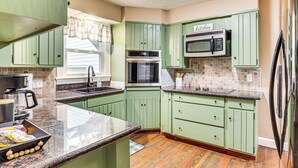 A kitchen with green cabinets, a microwave, and a refrigerator.