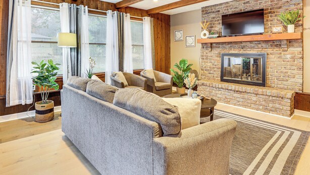 A living room with a sofa, armchairs, a fireplace, and a TV mounted on the wall.