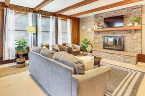 A living room with a sofa, armchairs, a fireplace, and a TV mounted on the wall. - Inviting Family Home, 2 Mi to Eastwood Mall! (Niles)