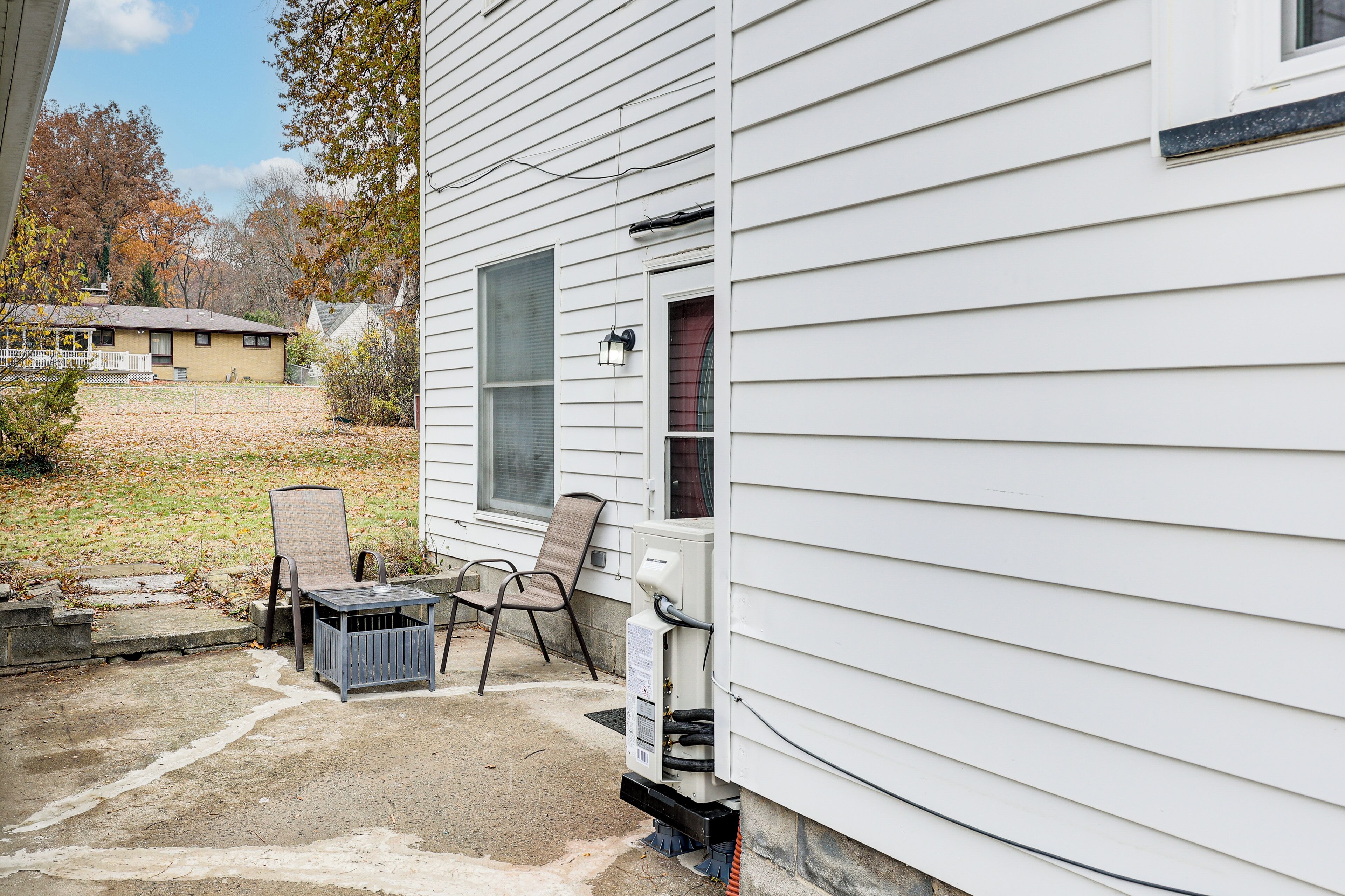 A house with a covered porch, two chairs, and a small table.