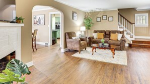 A spacious living room with hardwood flooring, a fireplace, a brown leather sofa, and a coffee table.