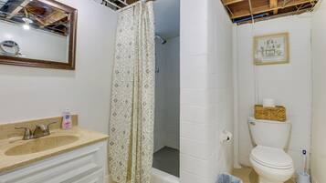 A bathroom with a sink, toilet, shower curtain, and a framed picture on the wall.
