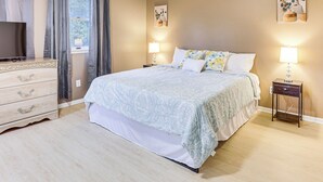 A bedroom with a bed, bedside tables, a dresser, and a TV.