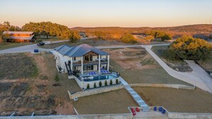 A large house with a swimming pool, a covered patio, and a view of the surrounding landscape. - Waterfront Home on Lake LBJ w/ Pool & Dock! (Kingsland)