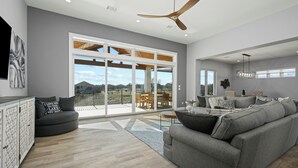 A spacious living room with a grey sofa, a black armchair, and a dining area with wooden furniture. - Waterfront Home on Lake LBJ w/ Pool & Dock! (Kingsland)