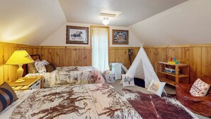 A cozy room with two beds, a wooden floor, a tent, and a bookshelf. - 1 BR Bunk House on Long Hollow Ranch, Dog Friendly (Sisters)