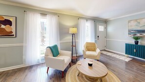 A living room with two white armchairs, a round wooden coffee table, a floor lamp, a teal cabinet, and a painting on the wall. - 6 Mi to Dtwn: 'macon Memories' Dog-friendly Haven (Macon)