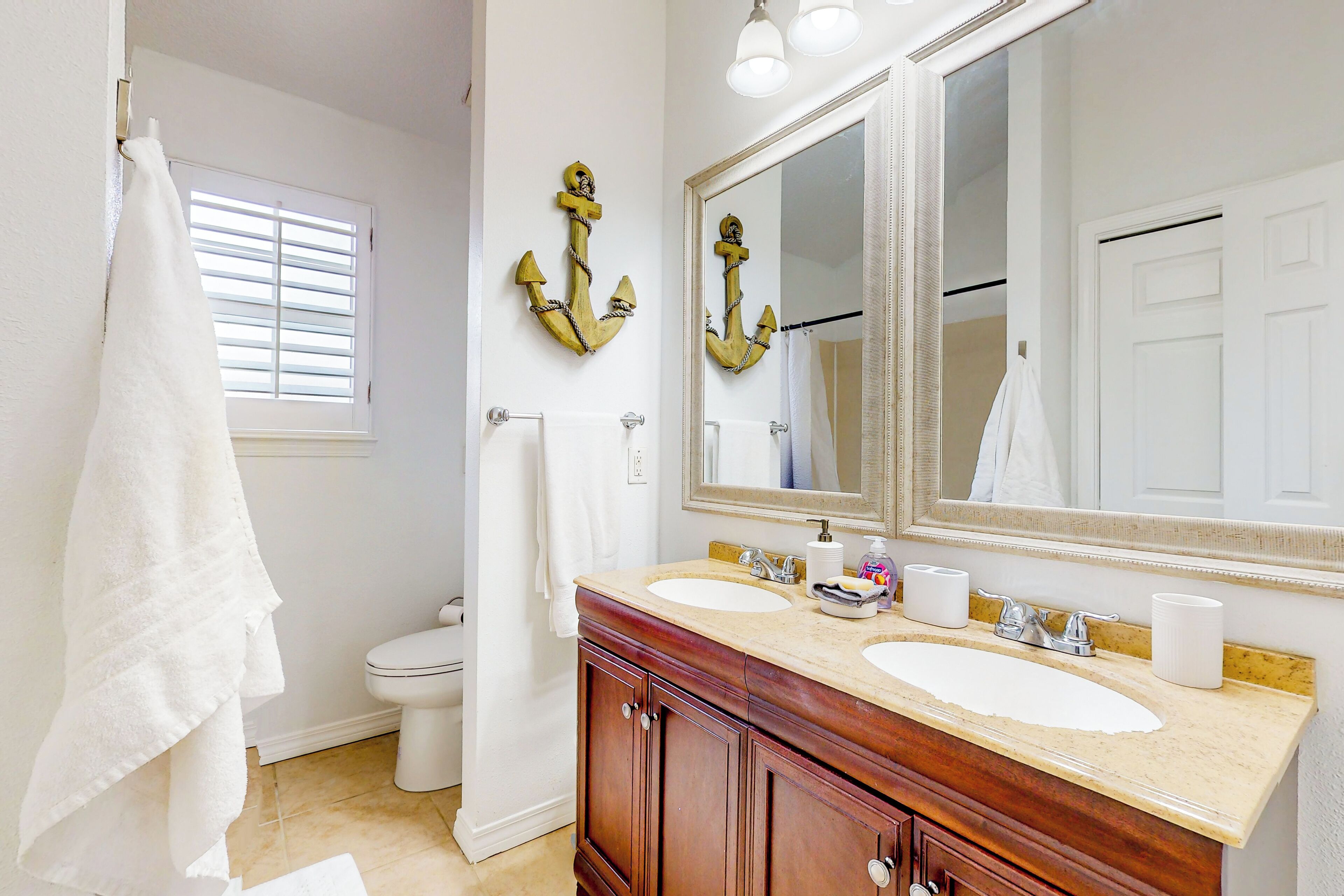 A bathroom with two sinks, a large mirror, and wooden cabinets.