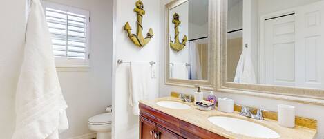 A bathroom with two sinks, a large mirror, and wooden cabinets.