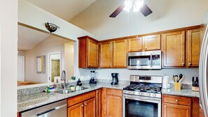 A kitchen with wooden cabinets, stainless steel appliances, granite countertops, and a ceiling fan. - Dog-friendly Yard! Retreat 11 Mi to Destin & Beach (Niceville)